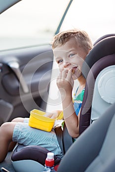 Happy little boy in the car eating