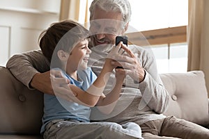 Happy senior grandfather and little grandson use smartphone