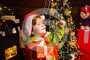 Happy little boy with Christmas gift is looking up. Happy child with Christmas gift. Portrait of Santa kid with gift