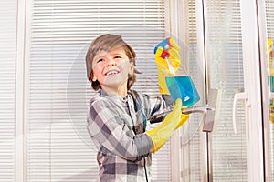 Happy little boy cleaning windows indoors