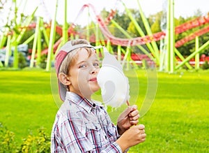 Happy little boy eating cotton candy