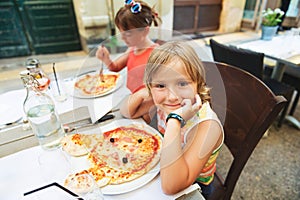 Happy little boy eating kid`s pizza in the restaurant.
