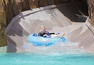 Happy little boy enjoying a wet ride down a water slide