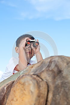 Happy little boy exploring outdoors clambering on a rock