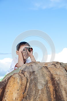 Happy little boy exploring outdoors clambering on a rock