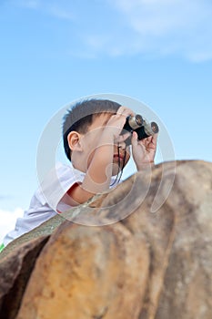 Happy little boy exploring outdoors clambering on a rock with te