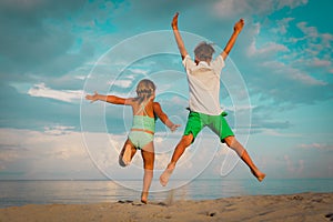 Happy little boy and girl play on beach, kids jump from joy