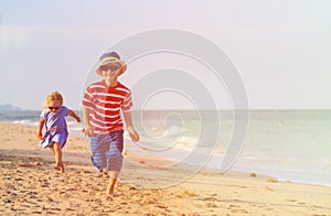 Happy little boy and girl running on sand beach