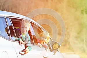 Happy little boy and girl travel by car in nature