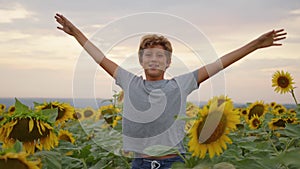 Happy little boy happy in the field with sunflowers. slow motion video. smelling big sunflower on summer field. Delight