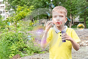 Happy little boy have fun blowing colorful shiny rainbow bubbles outdoors in the garden, summertime, outdoor play
