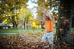 Happy little boy have fun playing with fallen golden leaves