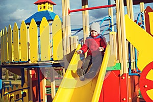 Happy little boy have fun and sliding on colorful modern playground in park.