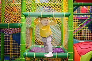 Happy little boy having fun in amusement in play center. Child playing on indoor playground