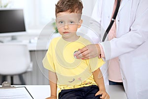 Happy little boy having fun while is being examine by doctor with stethoscope