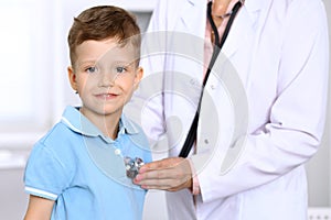 Happy little boy having fun while is being examine by doctor by stethoscope. Health care, insurance and help concept