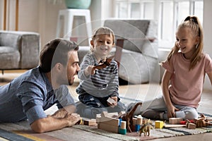 Happy little boy having fun with father and elder sister at home.