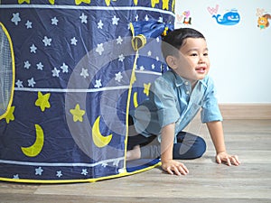 Happy little boy having fun with a play tent at home