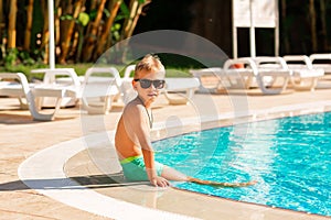 Happy little boy having fun at the pool at the resort