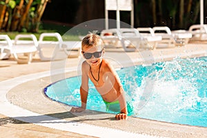 Happy little boy having fun at the pool at the resort