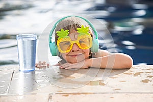 Happy little boy having fun in summer swimming pool. Family vacation.