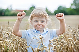 Happy little boy having fun in wheat field in summer