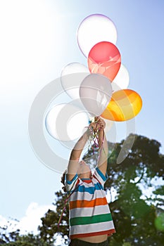 Happy little boy holding balloons