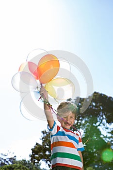 Happy little boy holding balloons