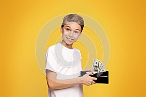 Happy little boy holding wallet with lots of dollars