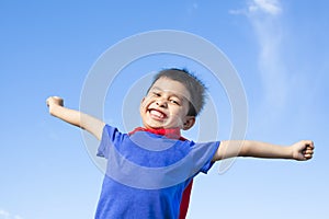 Happy little boy imitate superhero and open arms with blue sky photo