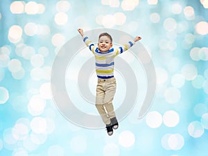 Happy little boy jumping in air over blue lights