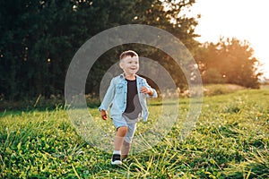 Happy little boy jumping on grass in summer day