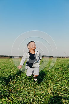 Happy little boy jumping on grass in summer sunny day