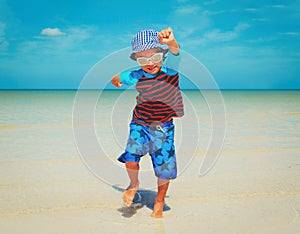 happy little boy jumping from joy on beach