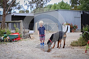Happy little boy jumping and splashing in puddle with rottweiler dog
