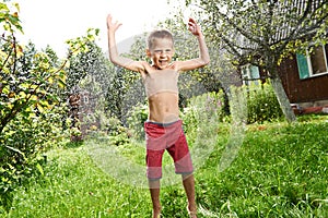 Happy little boy is jumping under rain