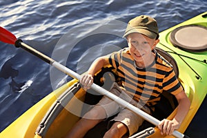 Happy little boy kayaking on river, above view. Summer camp activity