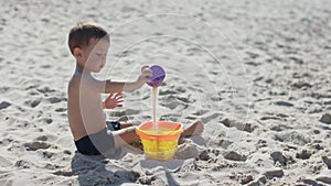 happy little boy kid playing white sand sea ocean shore coastline. male child