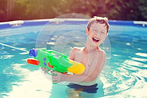 Happy little boy laugh and shoot with squirt gun photo