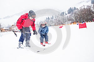 Happy little boy learning skiing with his father in Kitzbuhel ski resort, Tyrol, Austria