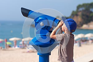 Happy little boy looking in telescope at Lloret beach