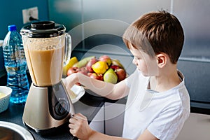 Happy little boy is making healthy fruit juice at home