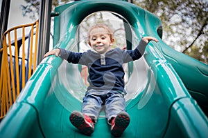 Happy little boy on the playground slide