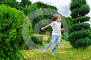 Happy little boy playing and jumping in the park