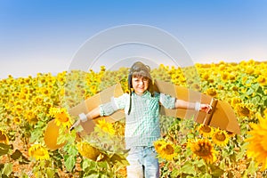 Happy little boy playing pilot in sunflower field