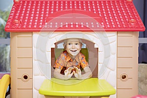 Happy little boy playing in a playhouse