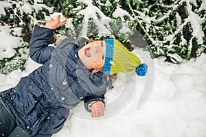 Happy little boy playing with snow outside