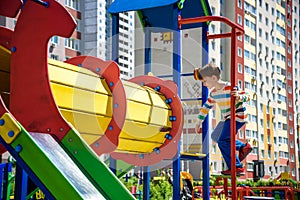 Happy little boy playing in tube or tunnel at the modern playground. Summer holidays. Happy and healthy childhood