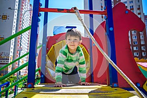 Happy little boy playing in tube or tunnel at the modern playground. Summer holidays. Happy and healthy childhood