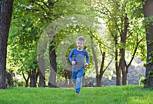 Happy little boy raning on the grass